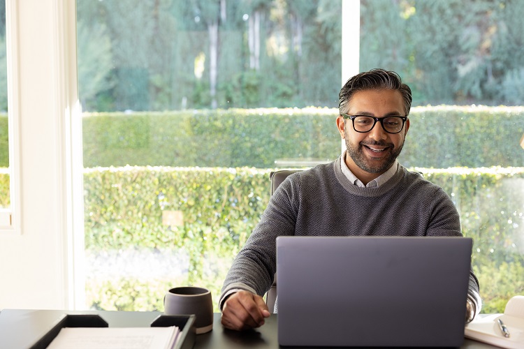 Man smiles while looking at laptop